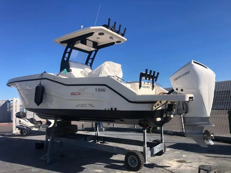 Seagame 230 X — Bateau à console centrale blanc équipé d’un moteur hors-bord sur remorque.