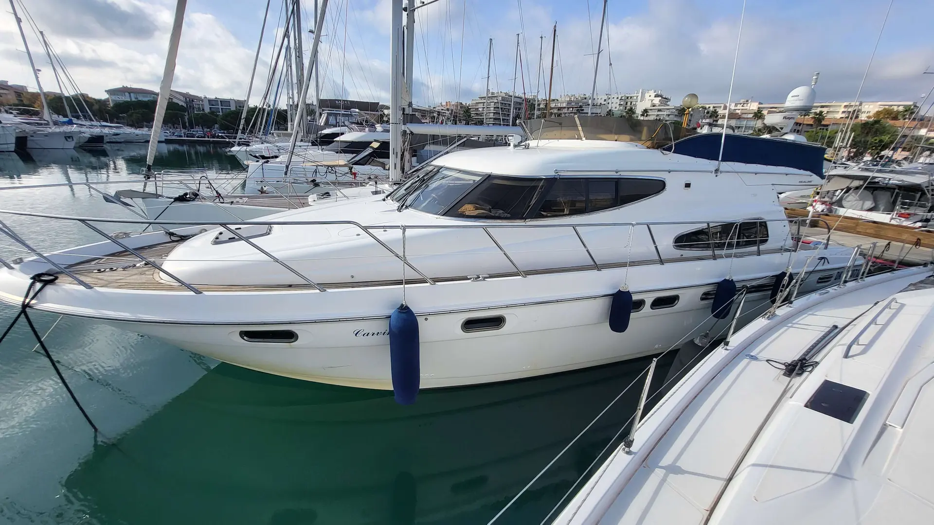 Sealine T 51 — Vedette à moteur blanche amarrée dans une marina, vue de profil.
