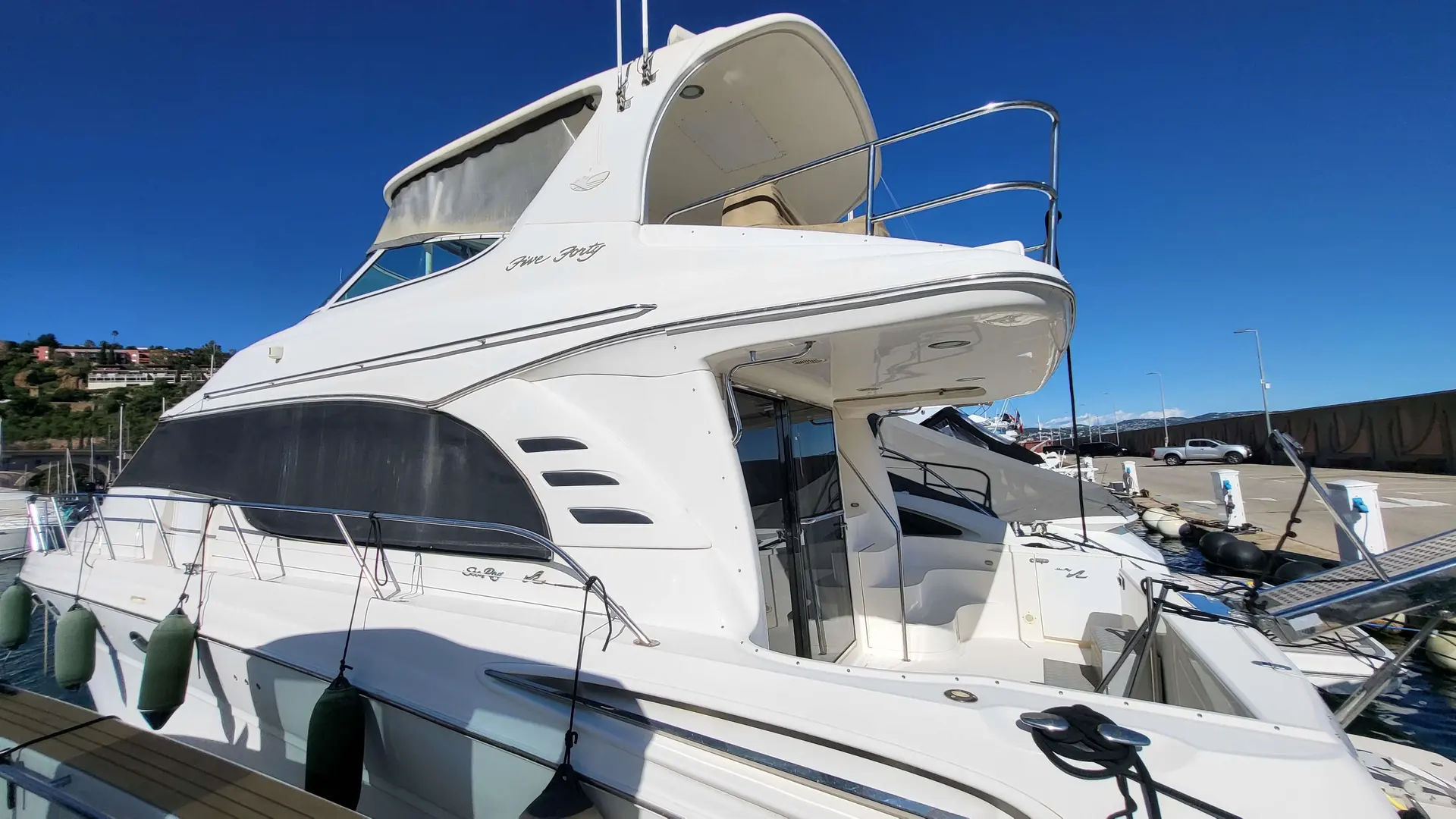 Sea Ray 54 — Vedette blanche amarrée, vue de trois quarts dans un port.