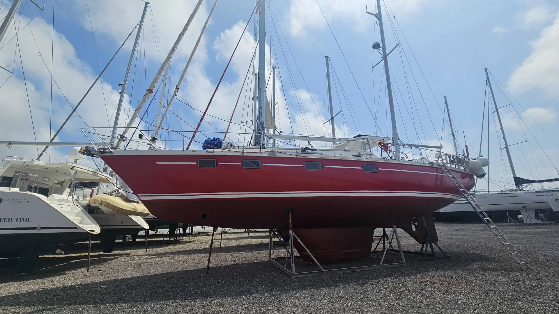 Amel Meltem — Voilier rouge présenté à terre sur bers dans un chantier nautique.