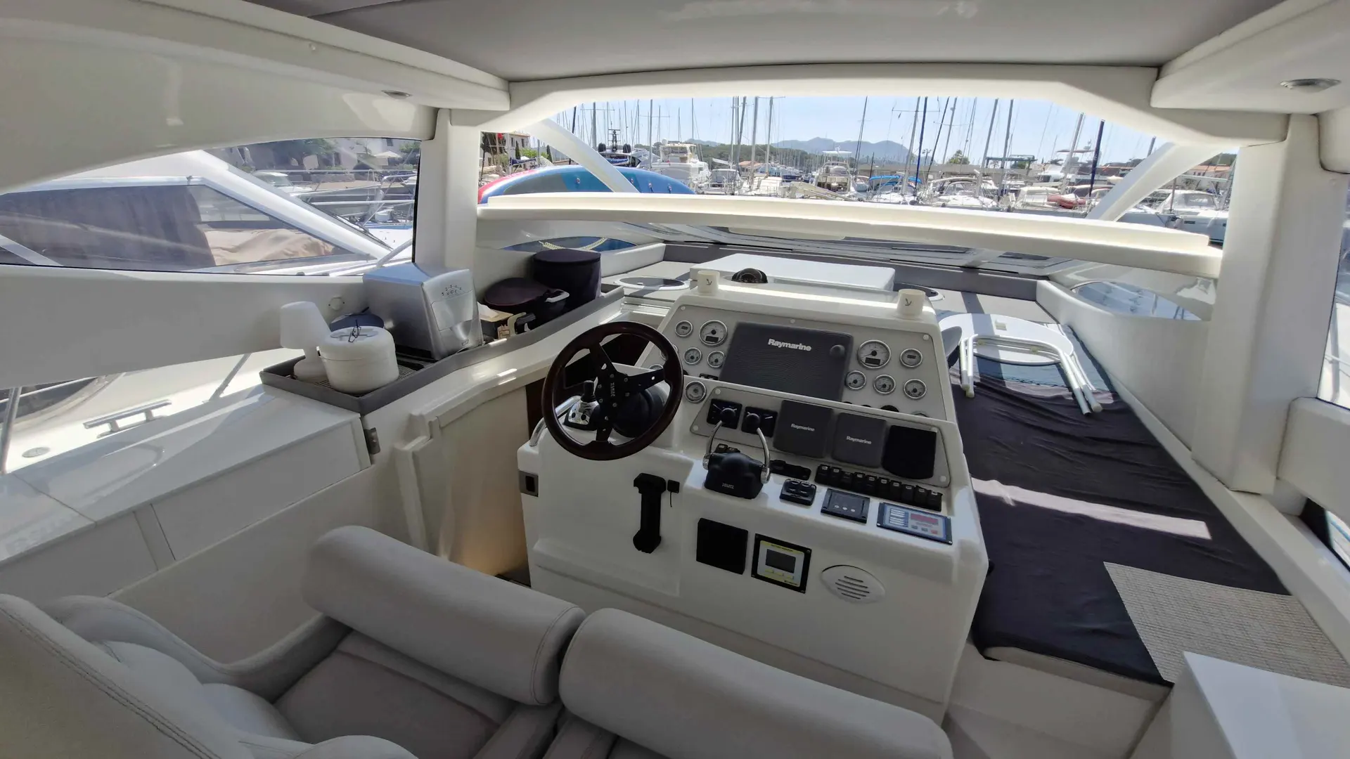 Innovazioni E Progetti Mira 44 — Poste de pilotage intérieur avec instruments, sièges et vue sur le port.