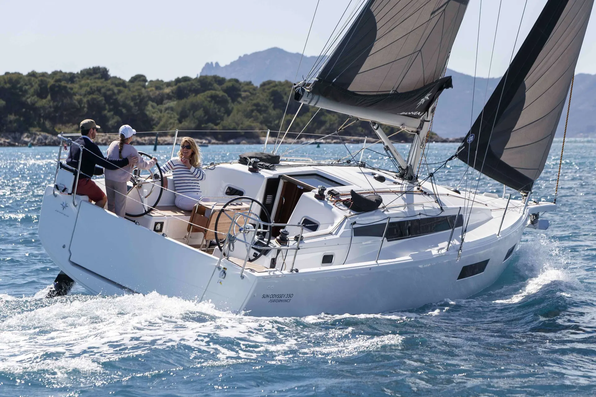Jeanneau sun odyssey 350 — Voilier blanc naviguant au large, toutes voiles hissées, avec trois personnes à bord.