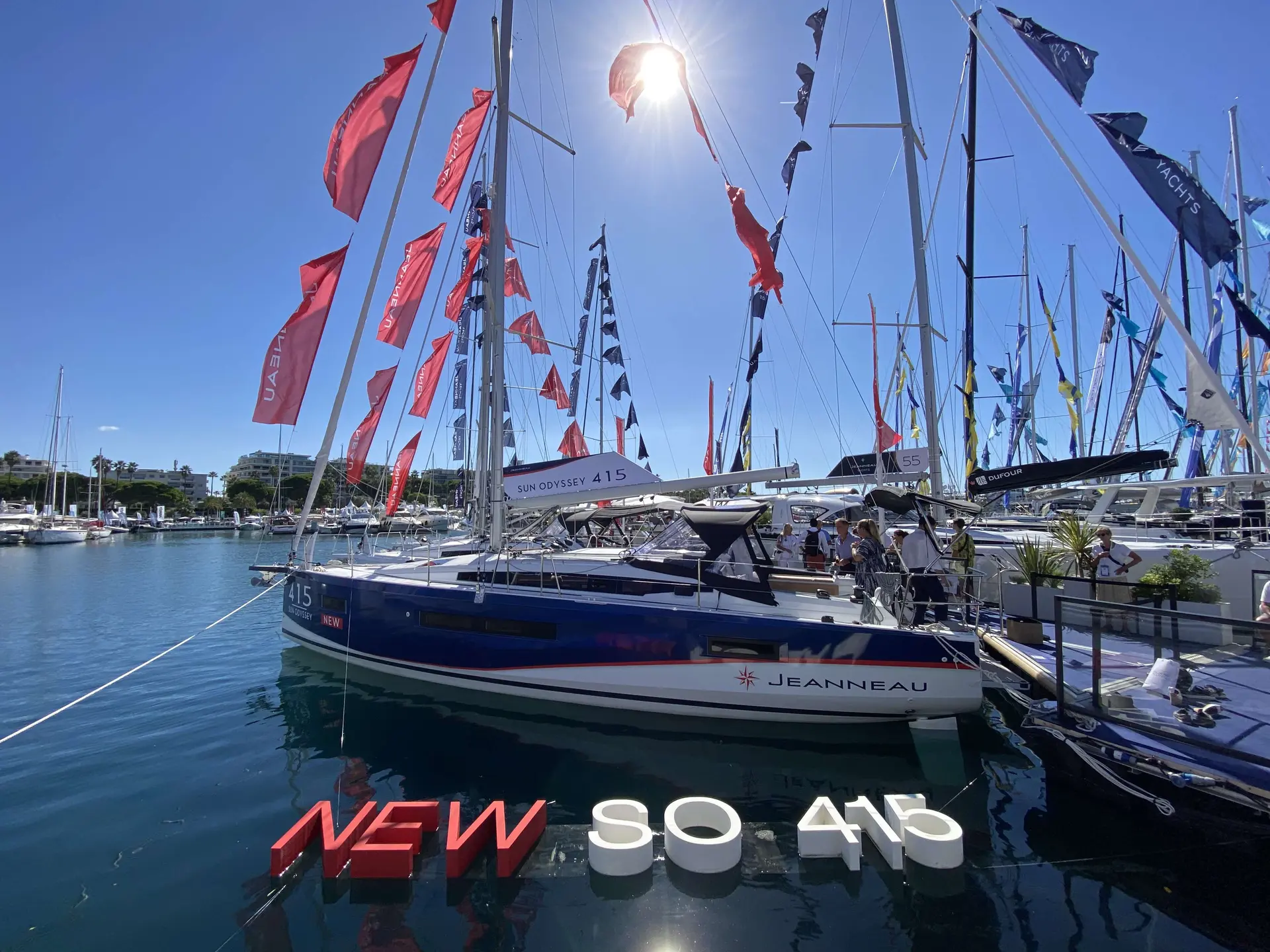 Jeanneau Sun Odyssey 415 — Voilier exposé à quai, vu de trois quarts, entouré de mâts et de pavillons.