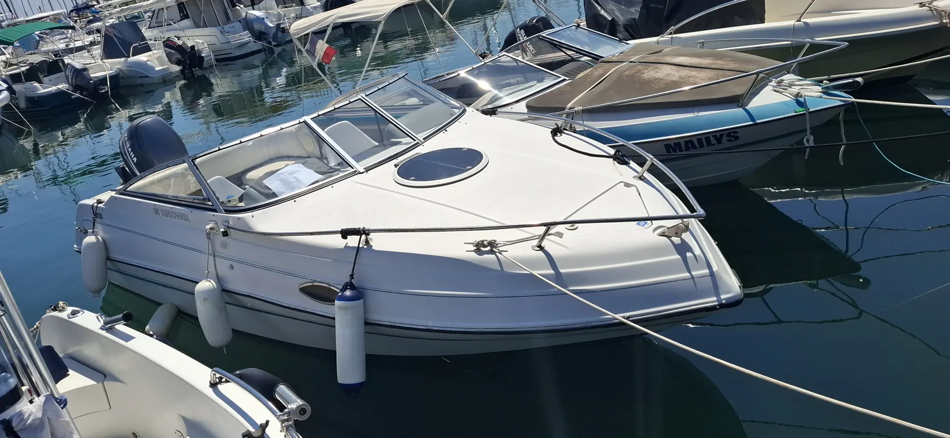 Four Winns Sundowner 195 — Bateau à moteur blanc amarré dans une marina, vu de trois quarts avant.