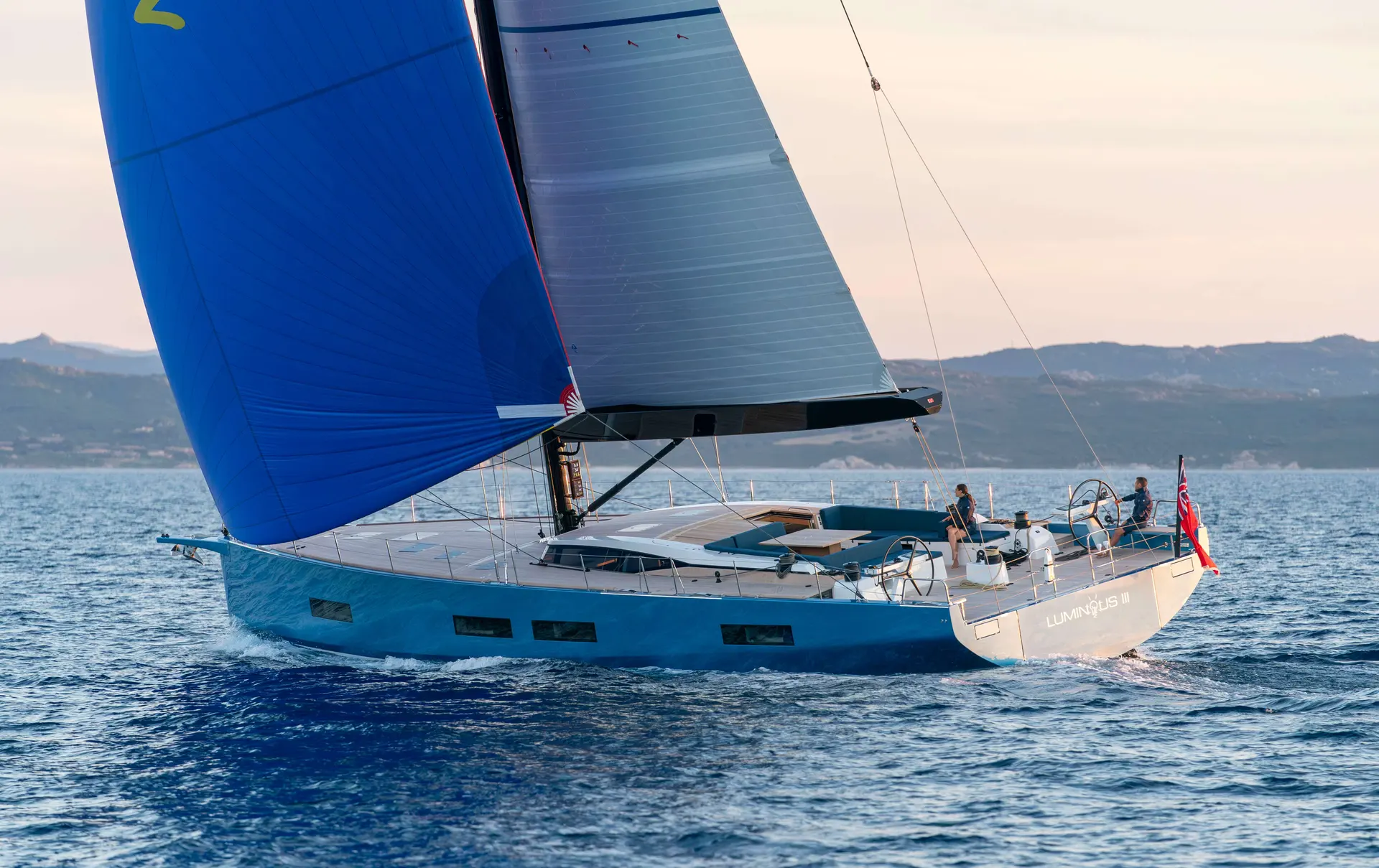 Solaris 74 RS — Voilier bleu naviguant sous voiles devant un littoral montagneux.