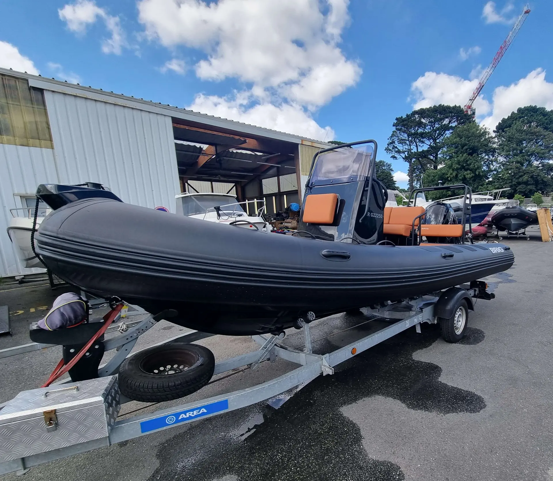 Brig Navigator 570 — Bateau pneumatique noir sur remorque, stationné devant un hangar.