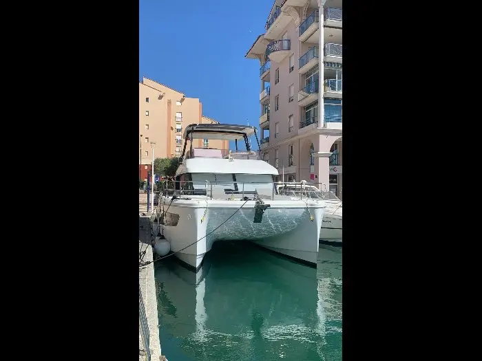 Fountaine Pajot My 40 — Catamaran vu de face, amarré dans un port entre des immeubles.
