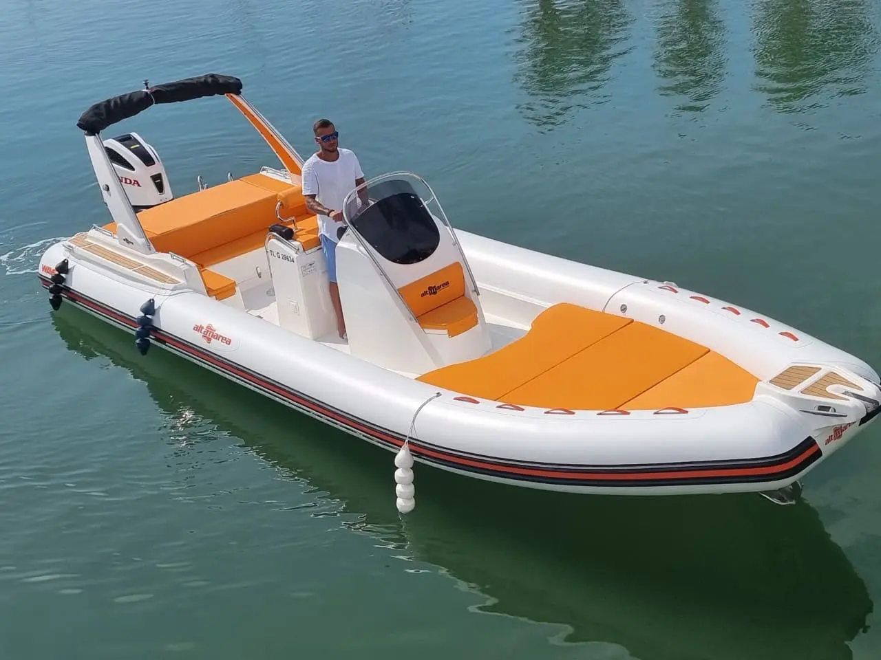 Altamarea Wave 27 — Bateau pneumatique blanc et orange vu de trois quarts sur l’eau, avec une personne à la barre.