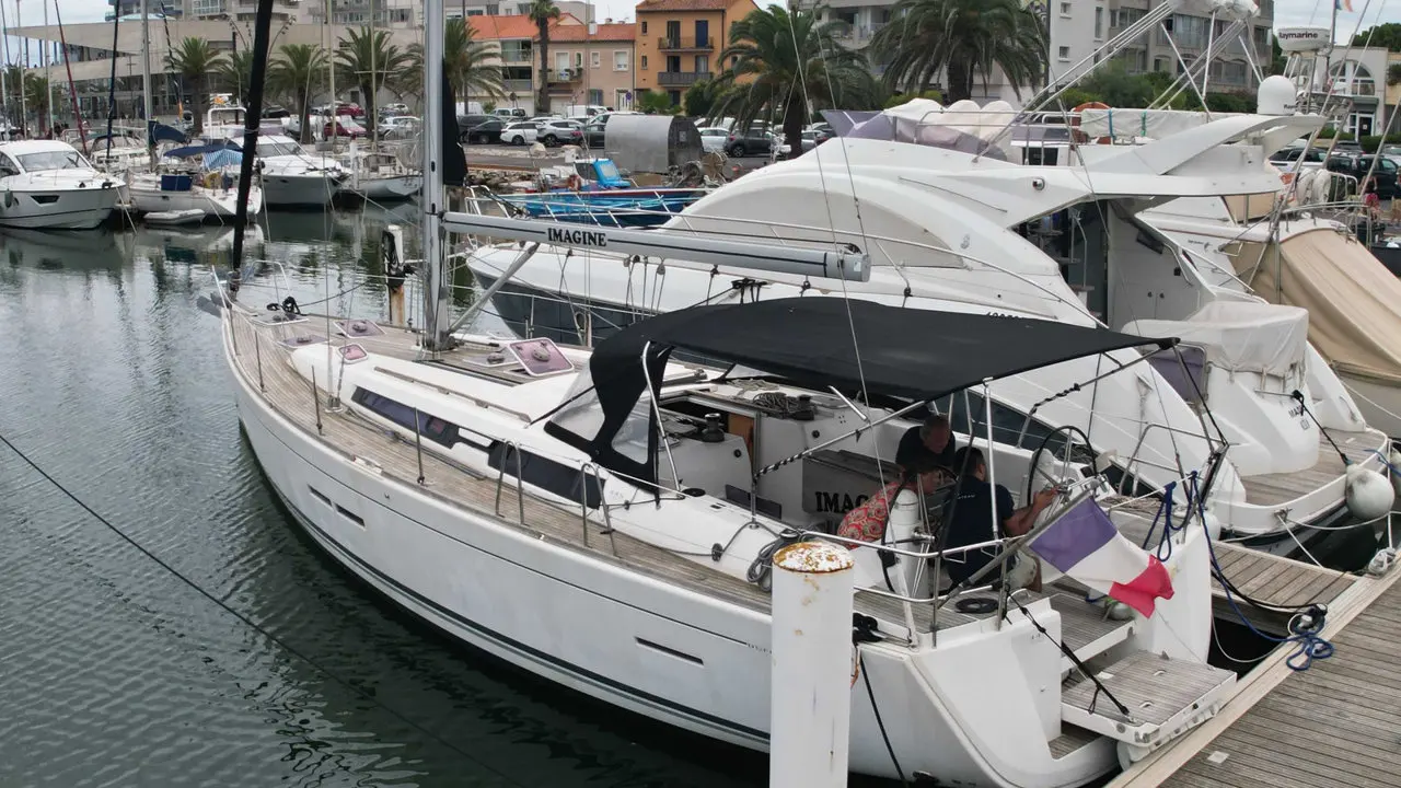 Dufour 445 — Voilier blanc amarré dans une marina, photographié de trois quarts arrière.