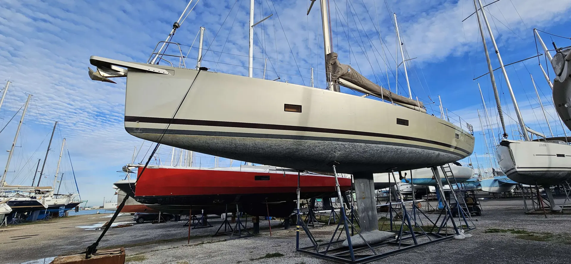 Sly Yachts 54 — Voilier blanc présenté à terre sur bers dans une aire de stockage nautique.