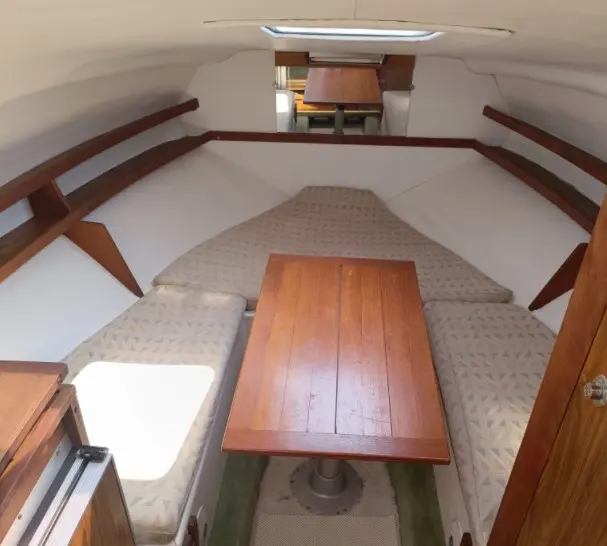Rocca Guepard — Vue intérieure d'une cabine avec couchettes, table en bois et banquettes.