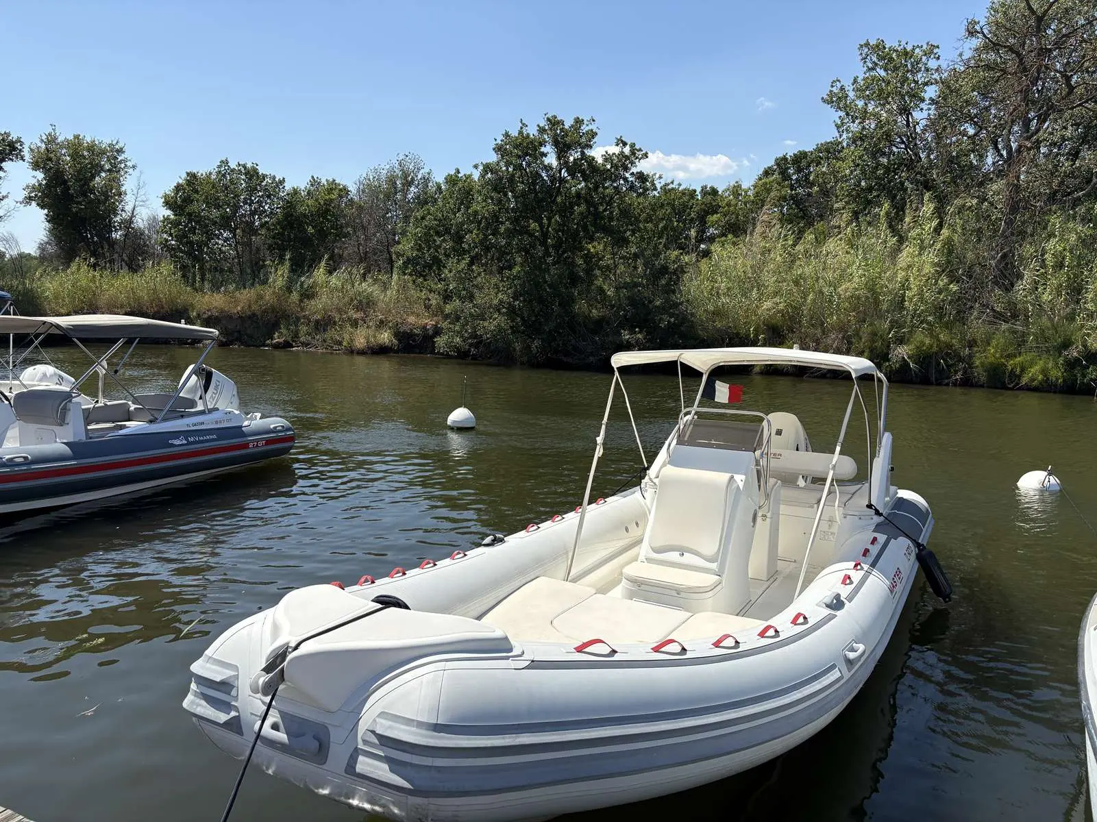 Master 730 Open — Bateau pneumatique blanc à console centrale amarré sur une rivière.