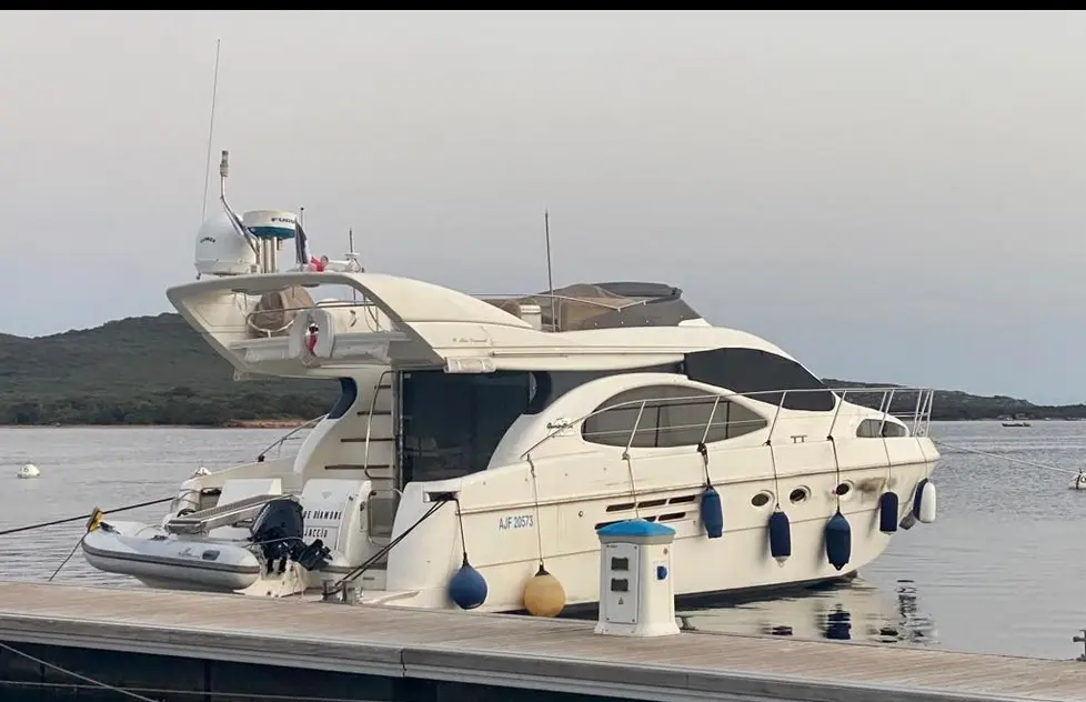 Azimut 46 — Bateau à moteur blanc amarré, vu de trois quarts arrière dans une marina.