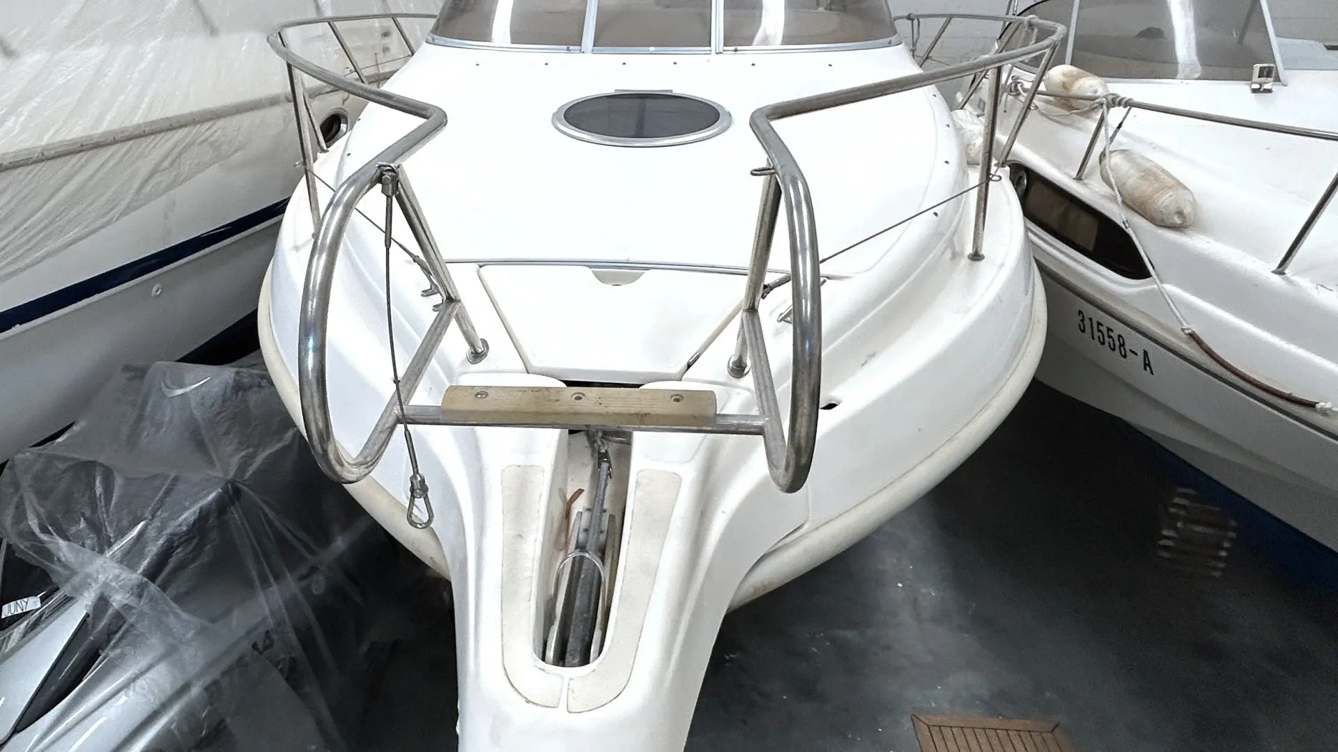 Cranchi Perla 25 — Vue plongeante sur l’avant d’un bateau blanc sous abri, entouré d’autres embarcations.