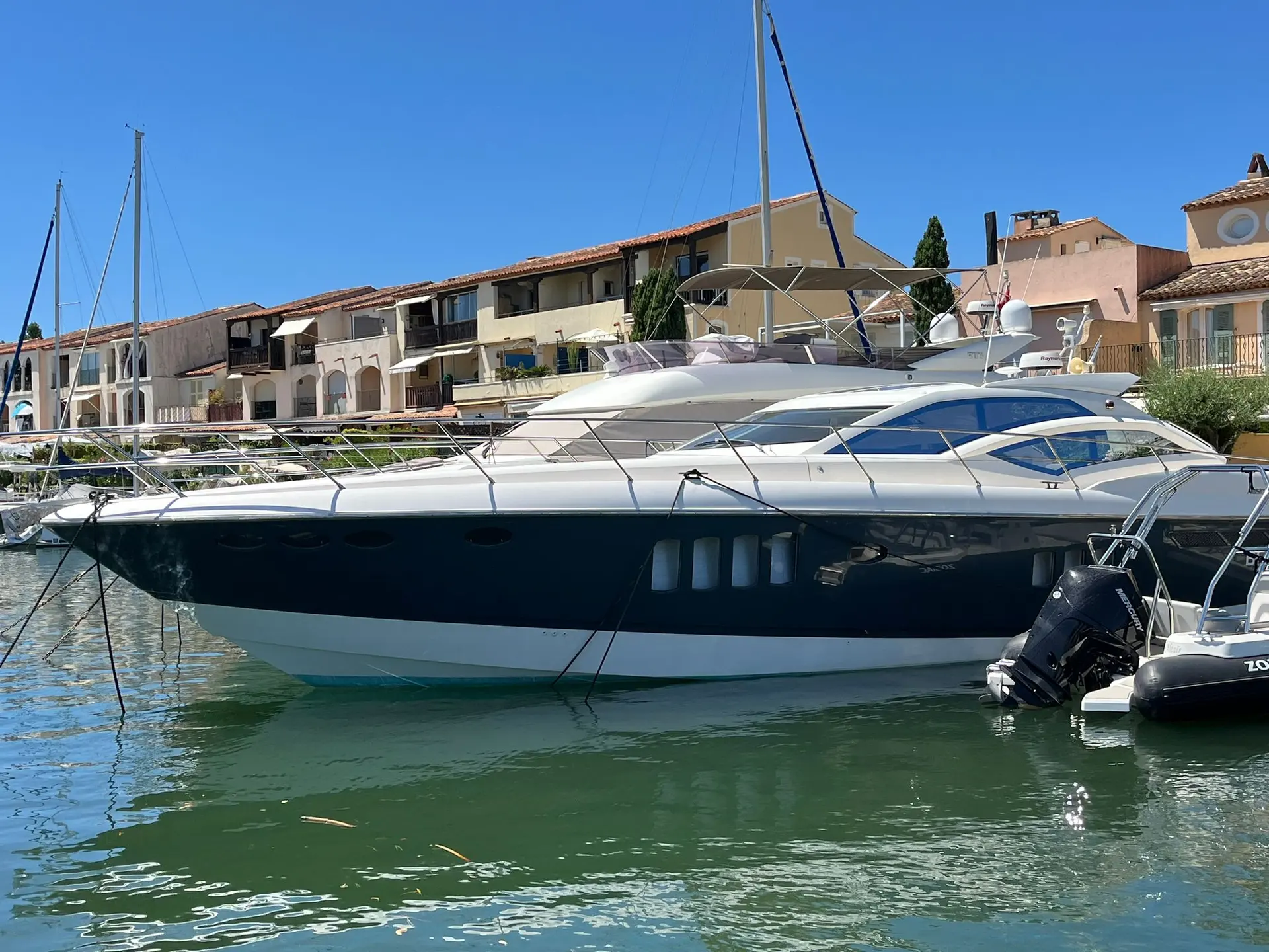 Absolute 56 — Bateau à moteur blanc et bleu amarré dans un port, vu de profil.