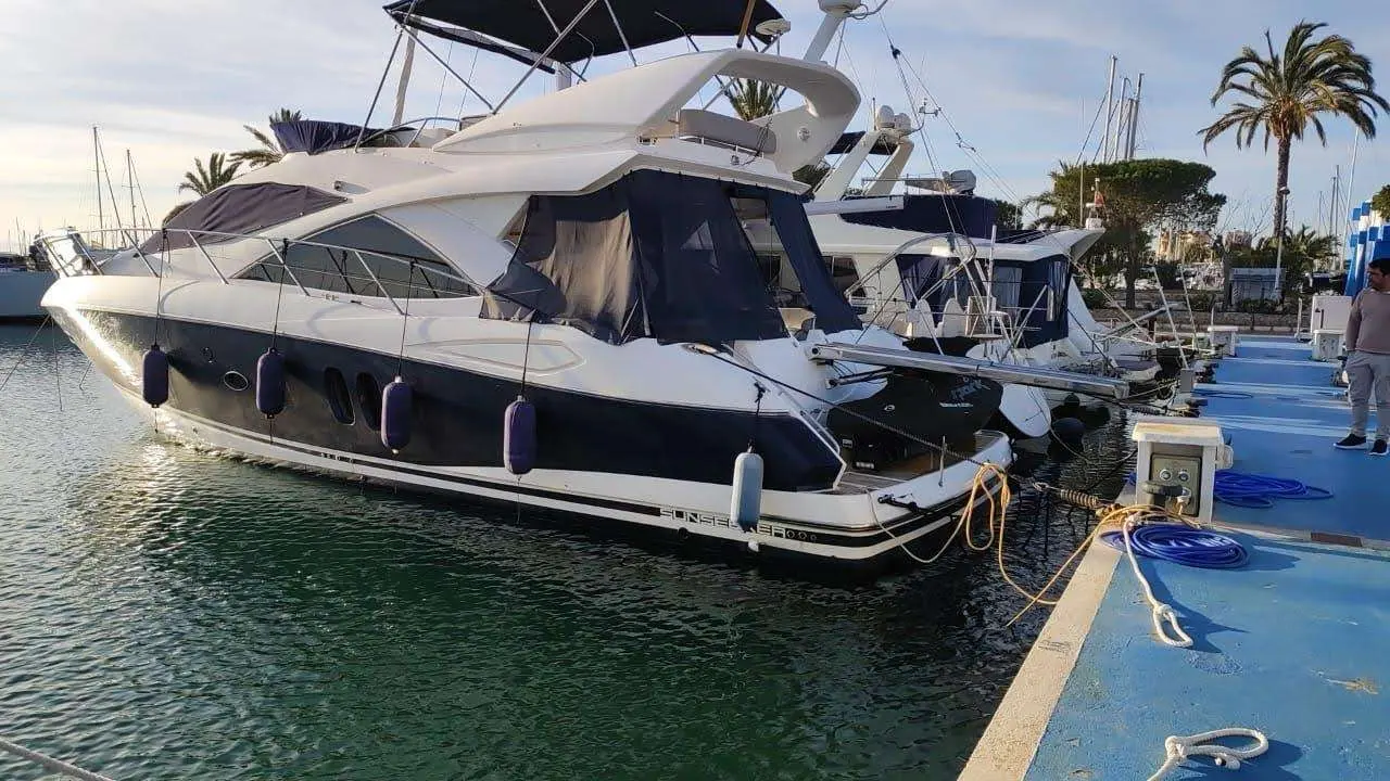 Sunseeker Manhattan 50 — Bateau à moteur blanc et bleu amarré dans une marina, vu de trois quarts arrière.