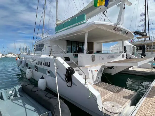 Squalt Marine International CK70 — Vue arrière trois-quarts d’un catamaran blanc amarré dans une marina.