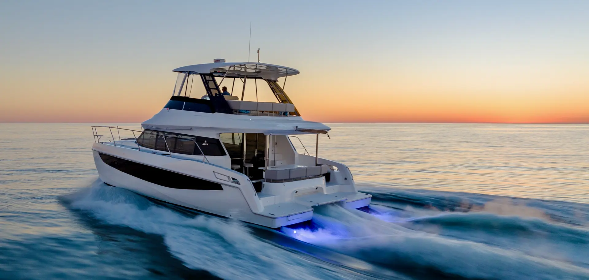 Aquila 42 Yacht — Bateau à moteur blanc vu de trois quarts arrière au coucher du soleil.