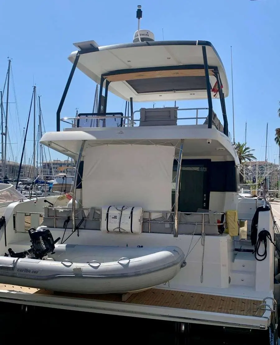Fountaine Pajot My 40 — Vue arrière d’un bateau à moteur amarré, avec annexe sur la plateforme.