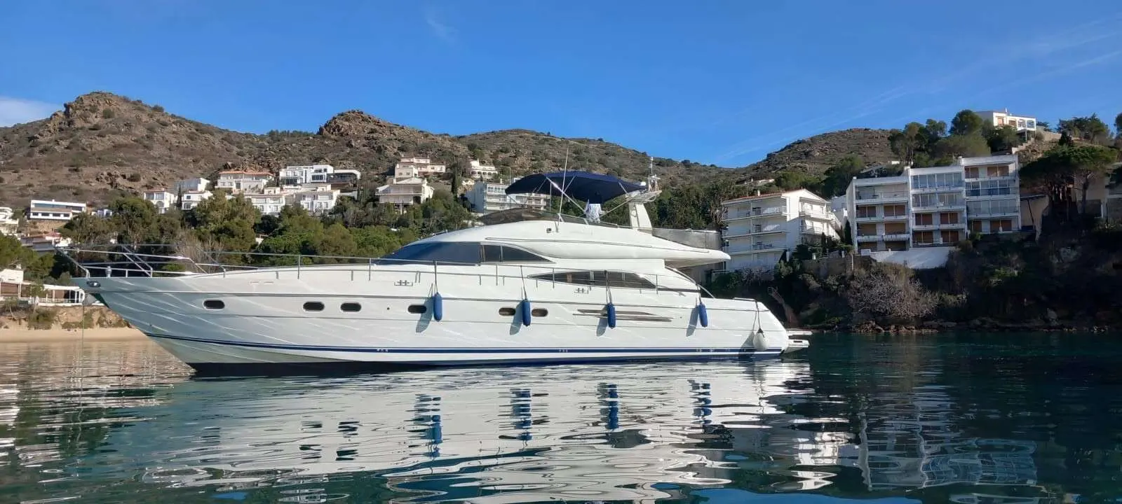 Princess 65 Fly — Yacht à moteur blanc vu de profil dans une baie, avec des collines en arrière-plan.