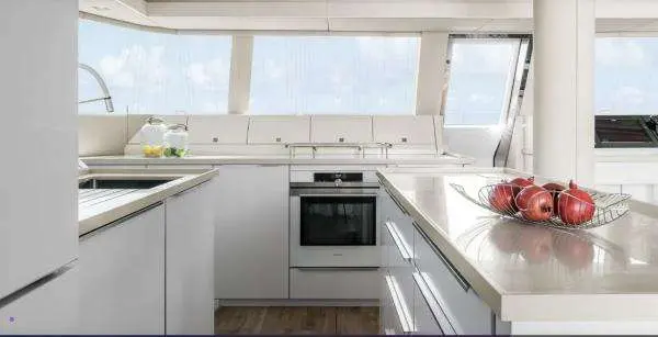 Sunreef Yachts Sunreef 50 — Cuisine blanche en U avec four intégré, plans de travail et larges vitrages.