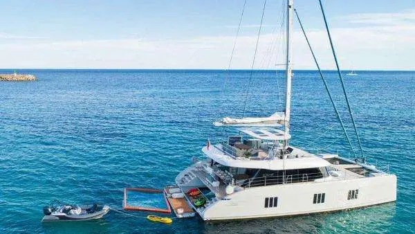 Sunreef Yachts Sunreef — Catamaran à voile vu de trois quarts depuis la mer, avec annexe à l’arrière.