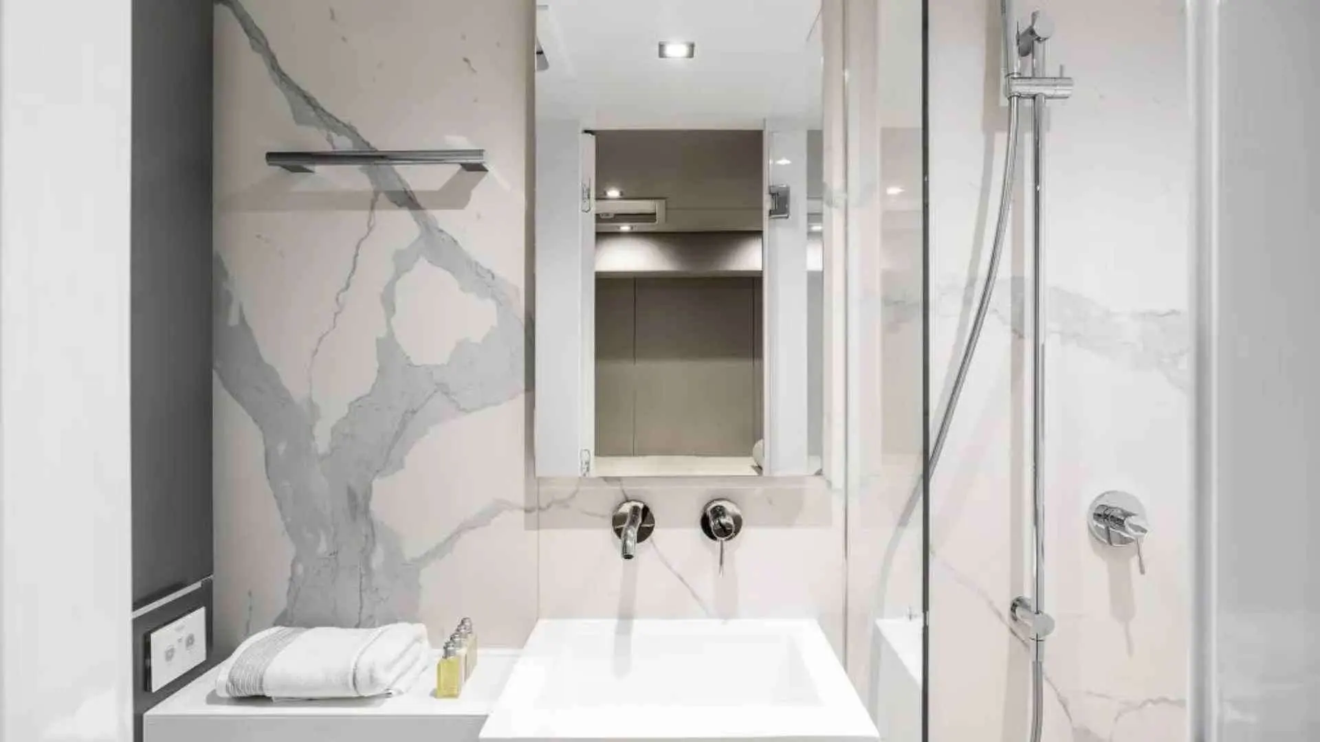 Sunreef Yachts Sunreef 50 — Salle de bains avec lavabo, douche vitrée et finitions effet marbre.