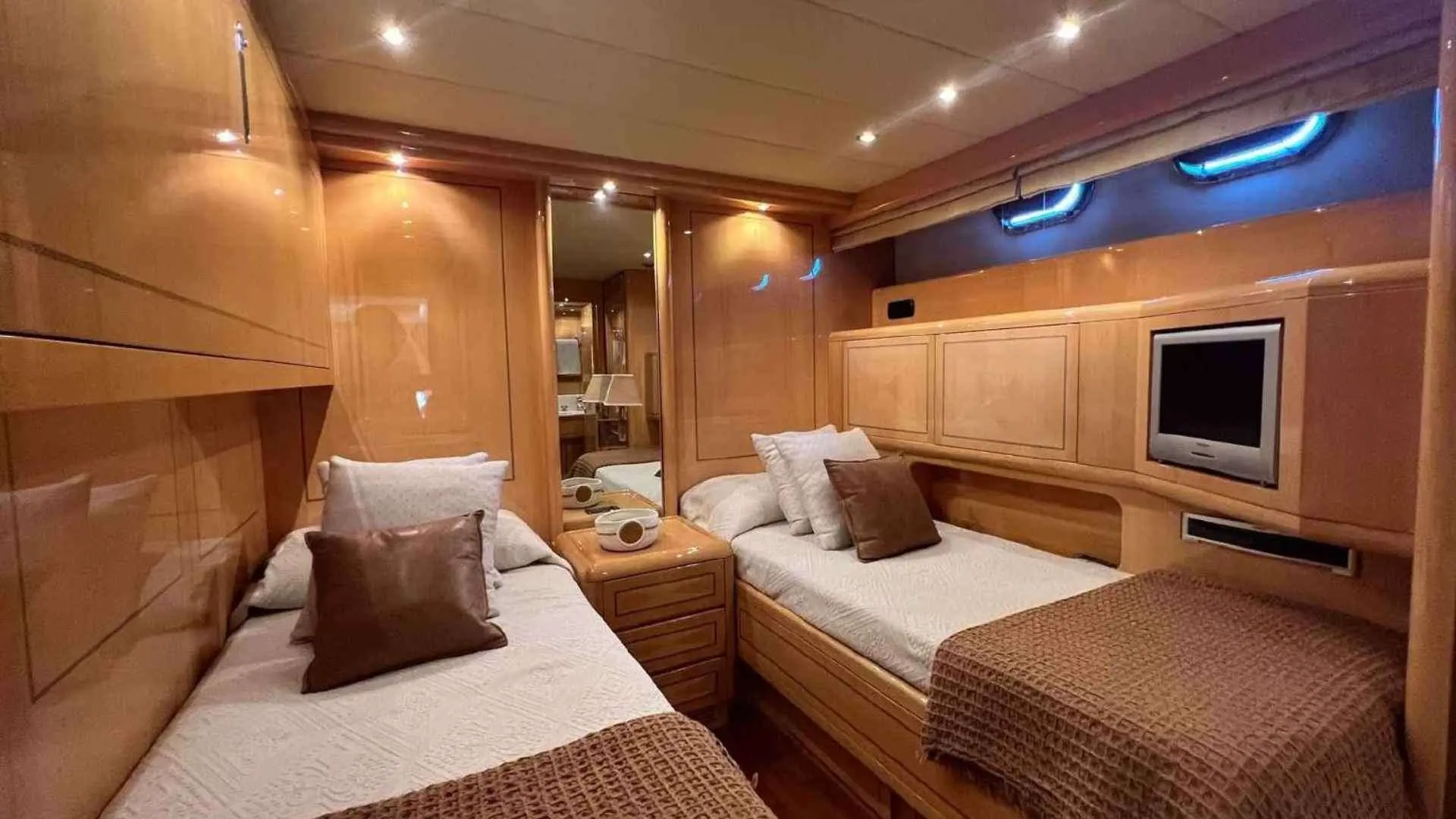 Mangusta 80 — Cabine intérieure avec deux lits simples, mobilier en bois et écran mural.