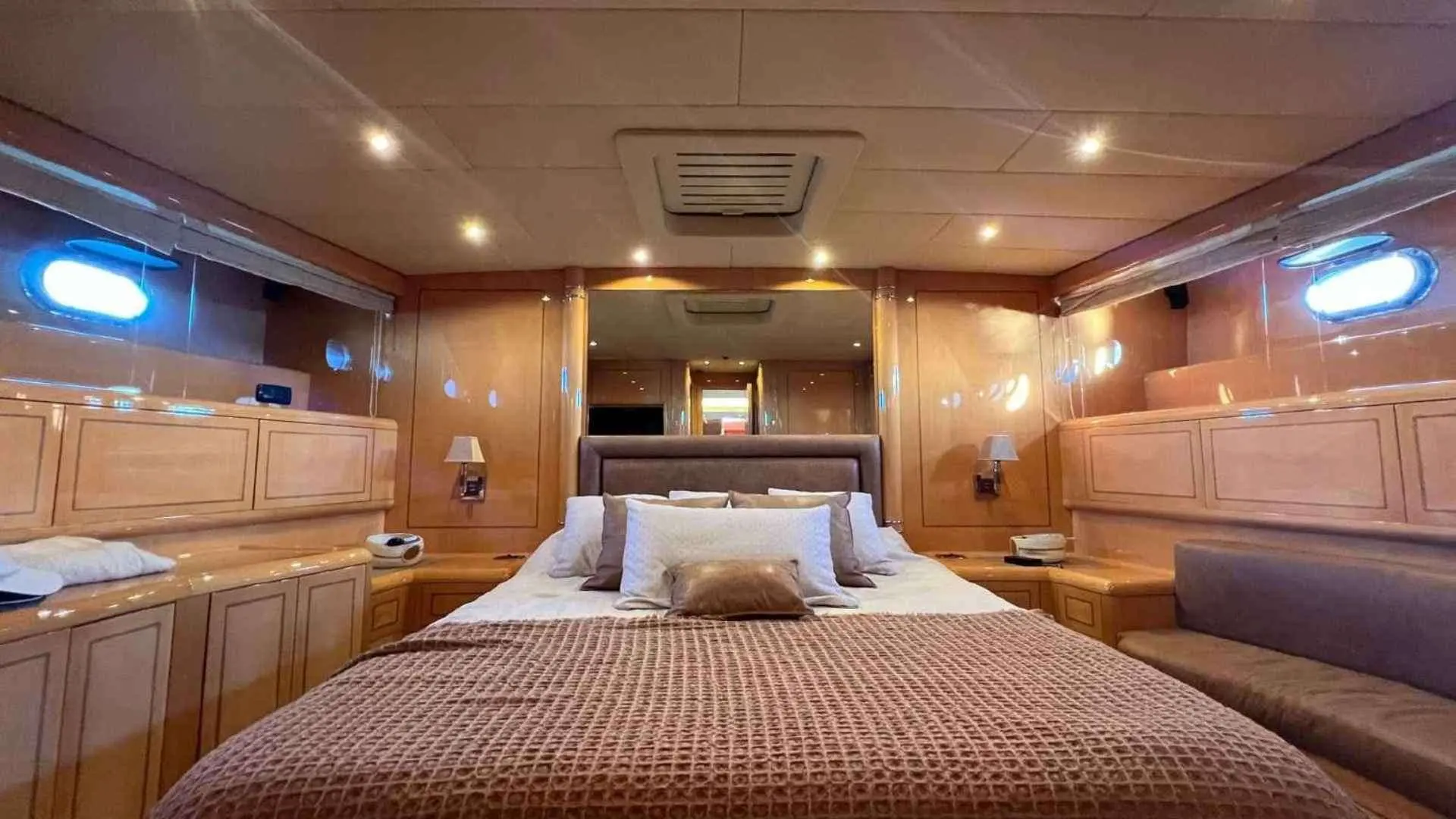 Mangusta 80 — Cabine avec lit double, boiseries, éclairage intégré et banquettes latérales.