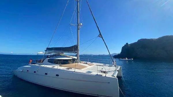 Fountaine Pajot Bahia 46 — Catamaran blanc au mouillage devant une côte rocheuse.