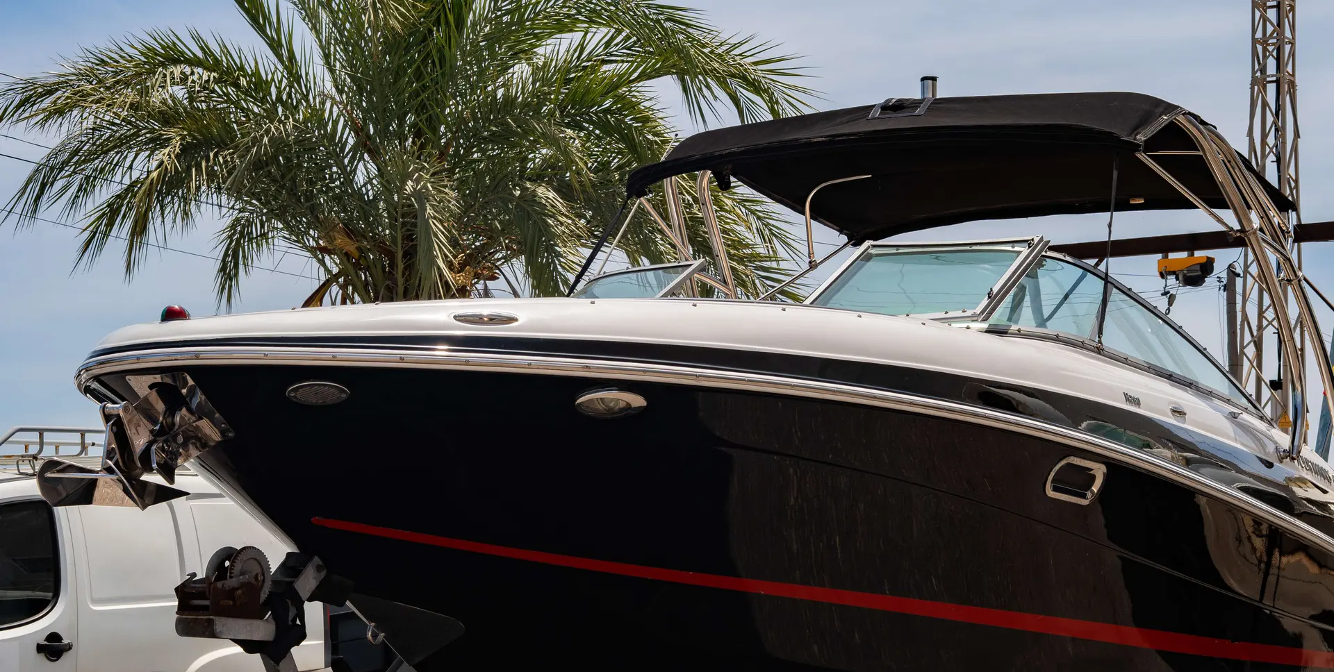 Four Winns Horizon 260 — Vue rapprochée de la coque noire et du cockpit couvert d’un bateau à moteur.