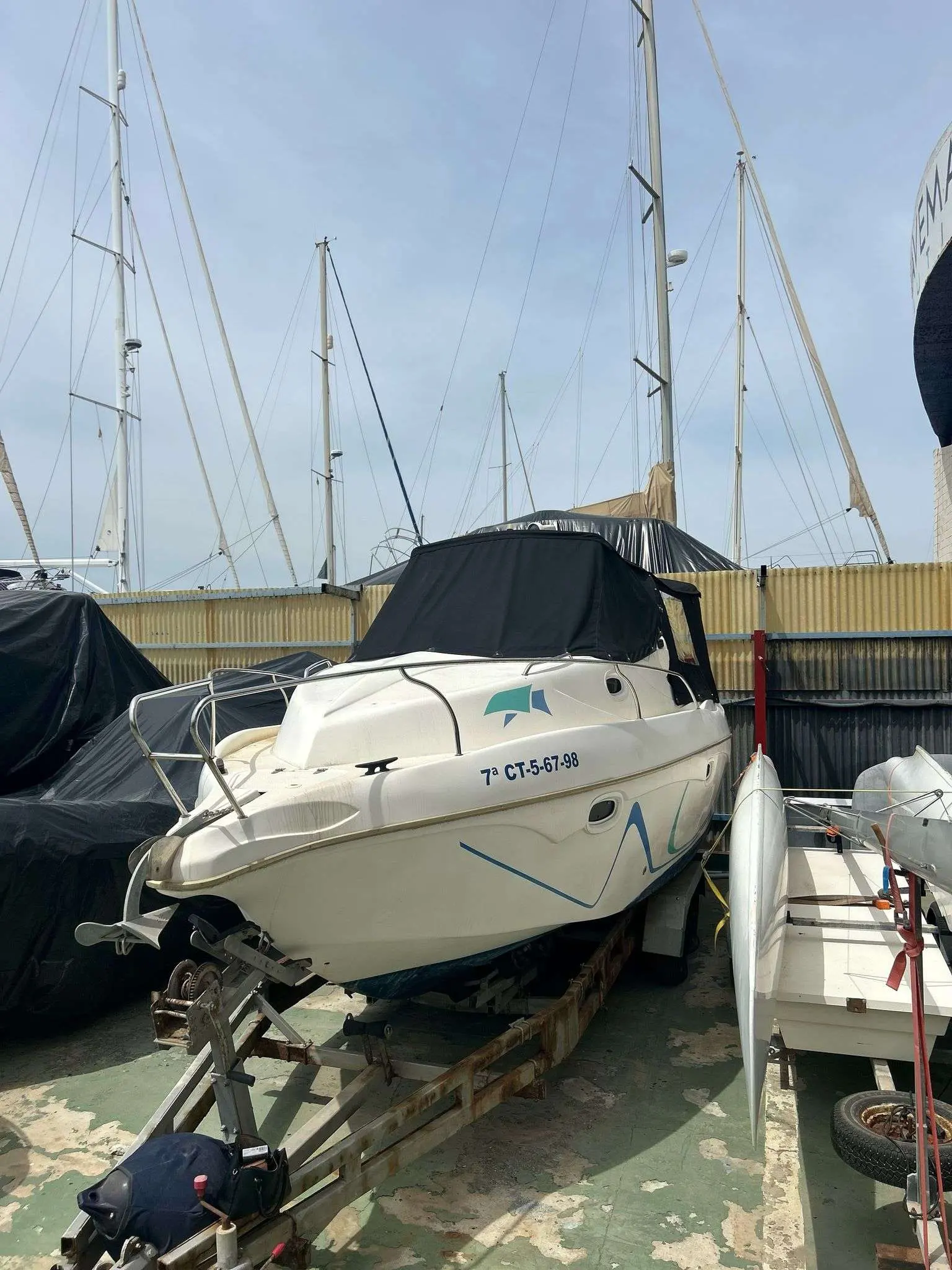 Lema Gold — Bateau à moteur blanc bâché, photographié sur sa remorque dans un chantier nautique.