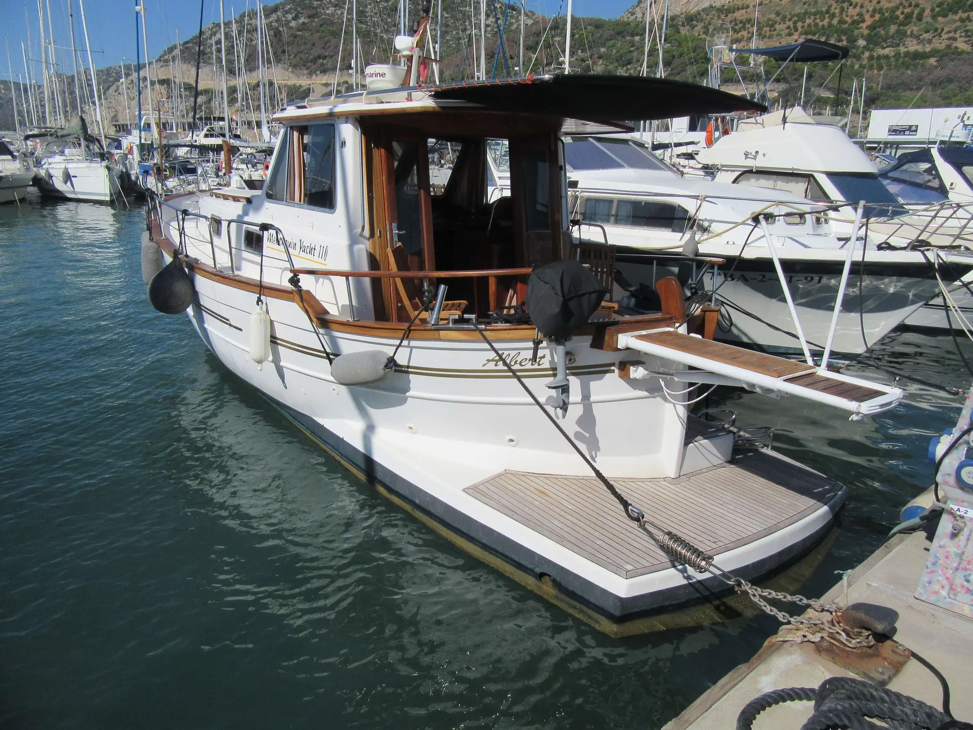 Menorquin 110 — Bateau à cabine amarré dans un port, vu de trois quarts arrière.