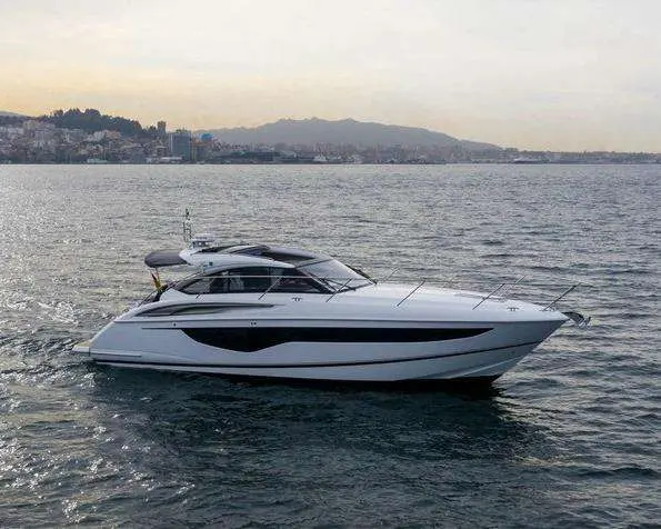 Princess V40 — Bateau à moteur blanc vu de profil sur l’eau, avec une côte en arrière-plan.