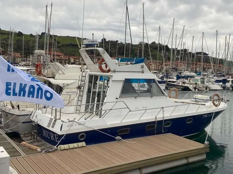 Guy Couach 1000 — Vedette à moteur blanche et bleue amarrée dans un port de plaisance.