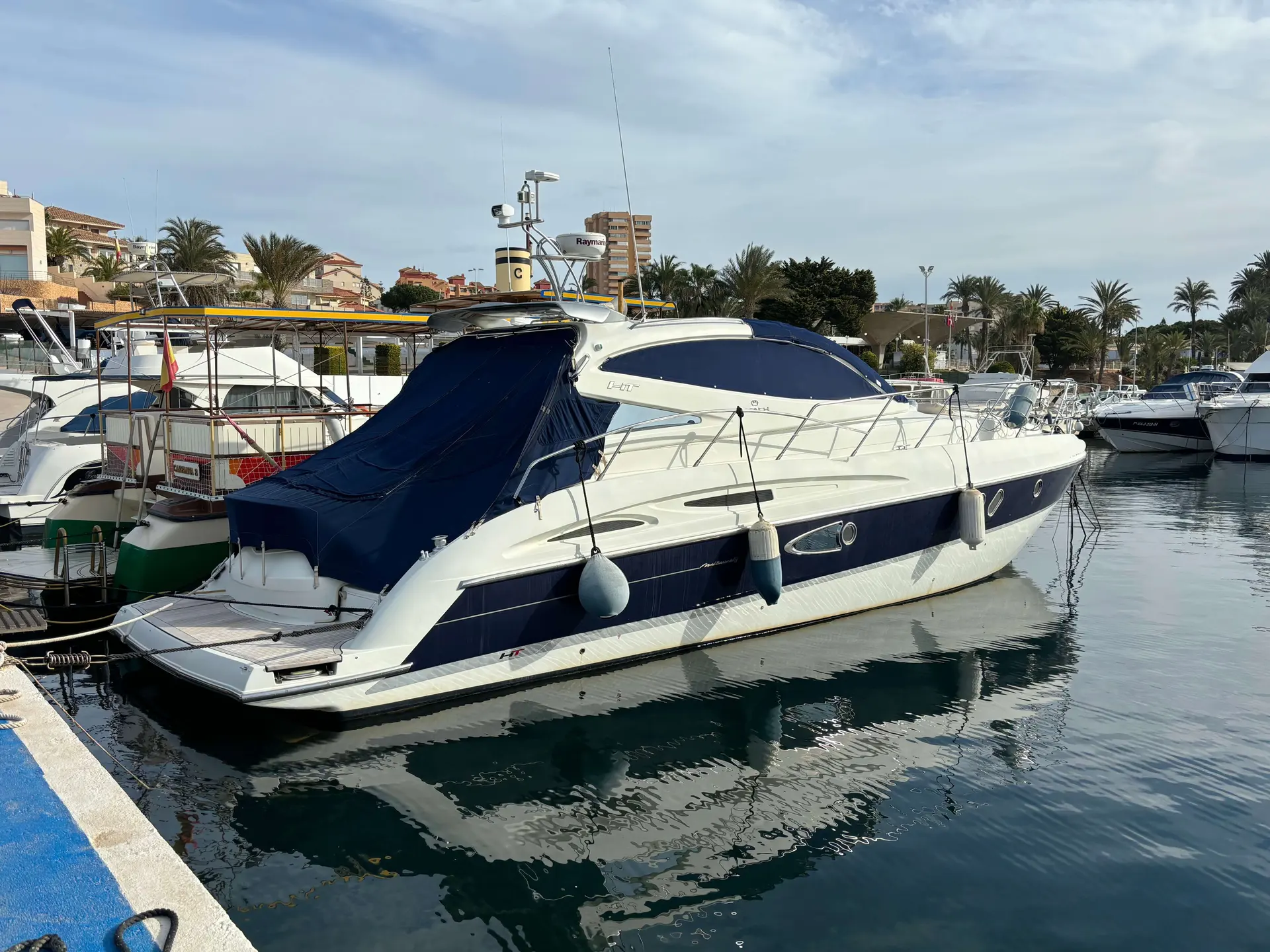Cranchi Mediterranee 47 — Bateau à moteur amarré dans une marina, vu de trois quarts arrière.