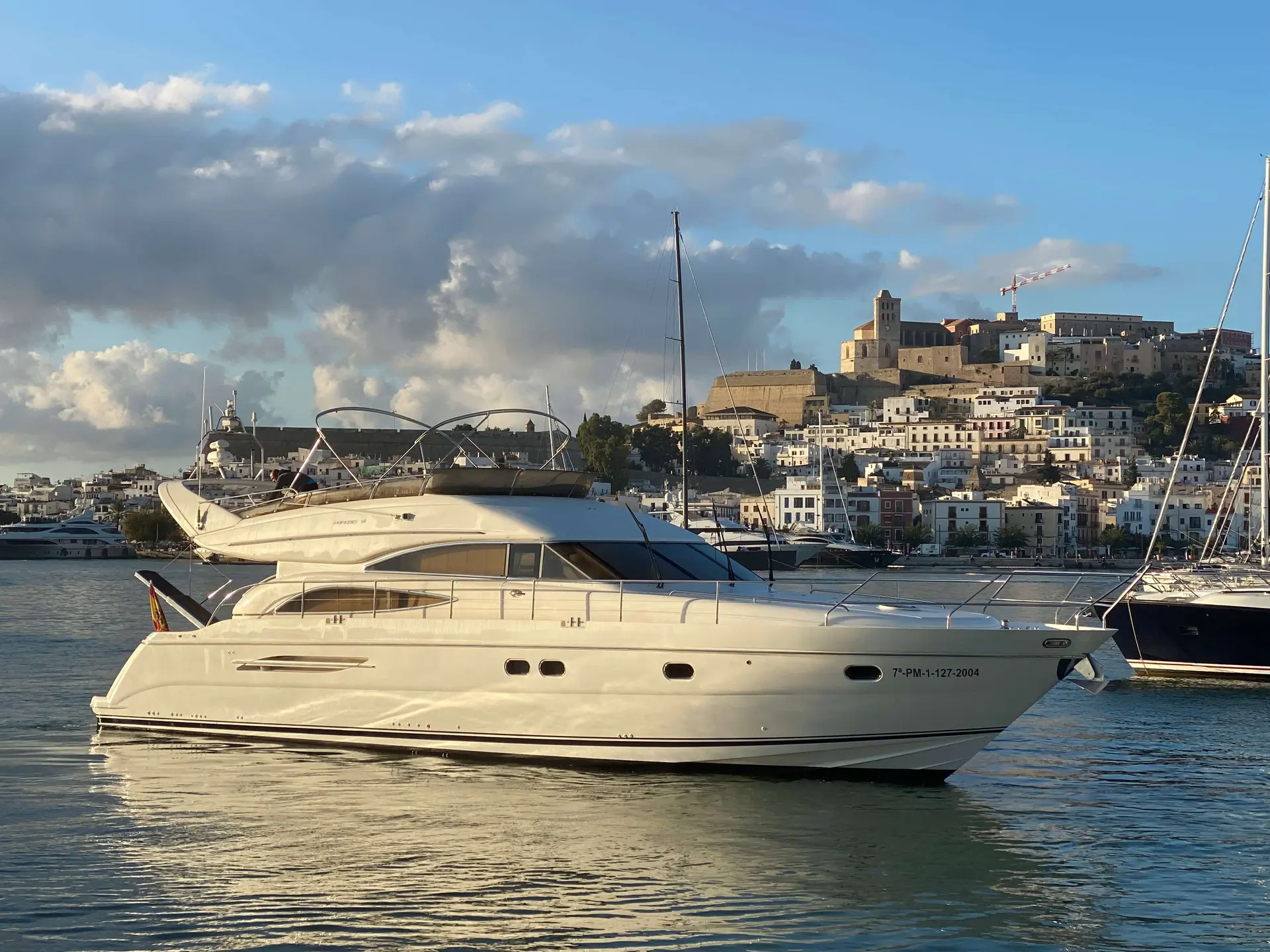 Princess 61 — Bateau à moteur blanc vu de profil dans un port, avec une ville en arrière-plan.