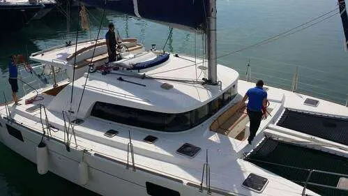 Lagoon 440 — Vue en plongée d’un catamaran blanc amarré, avec plusieurs personnes à bord.