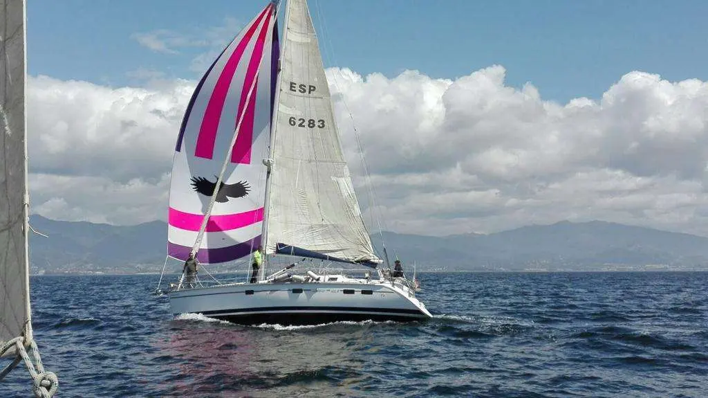 Hunter 40.5 — Voilier naviguant au large sous voiles, avec des montagnes en arrière-plan.