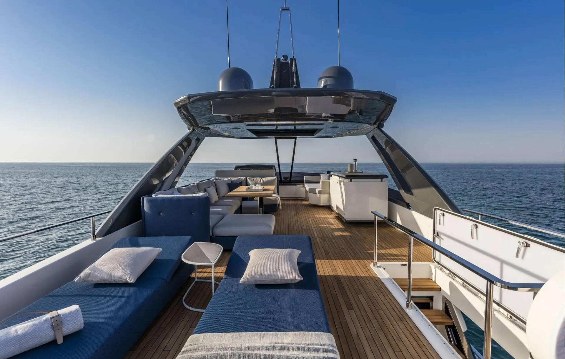 Ferretti 780 — Pont extérieur d’un yacht avec bains de soleil, salon et mer en arrière-plan.