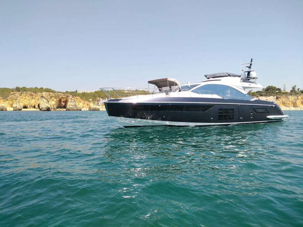 Azimut S7 — Bateau à moteur vu de profil au mouillage devant une côte rocheuse