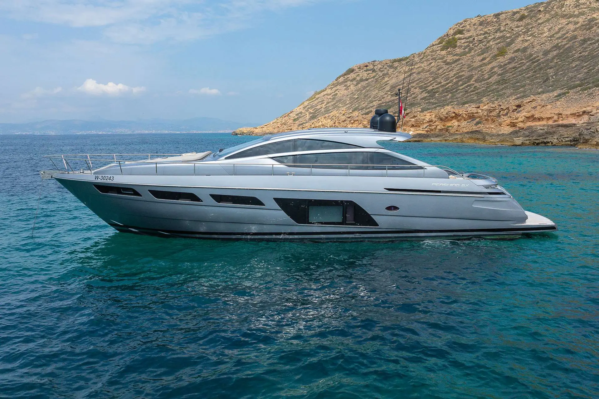 Pershing 6X — Bateau à moteur gris photographié de profil dans une baie aux eaux turquoise.