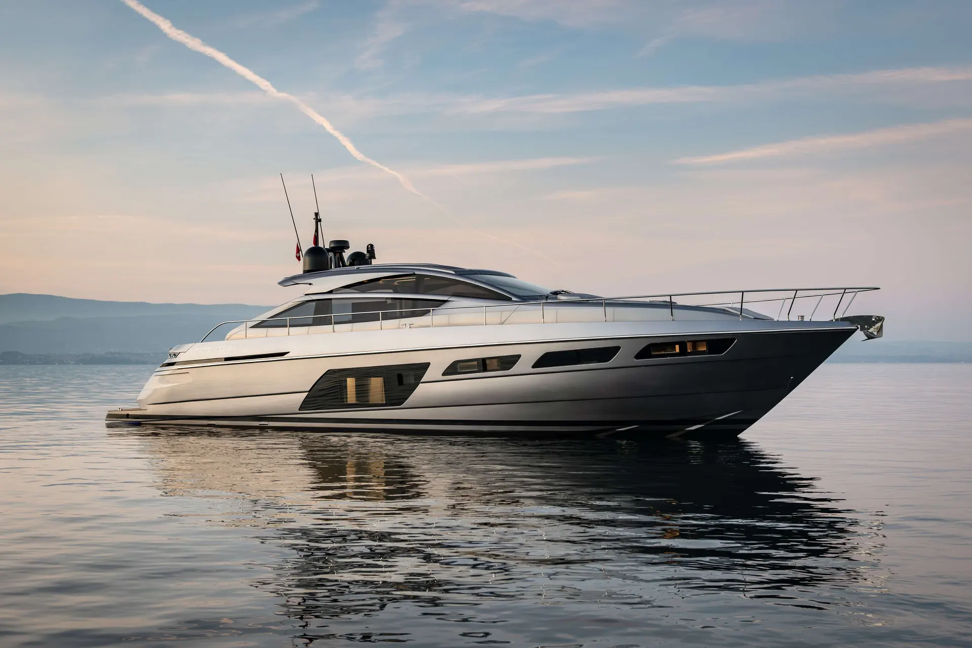 Pershing 6X — Vue latérale trois-quarts d’un yacht à moteur blanc et gris sur une mer calme.