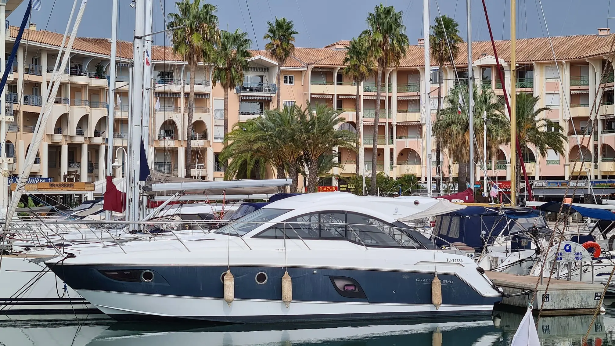 Beneteau Gran Turismo 38 — Bateau à moteur blanc et bleu amarré dans un port de plaisance.
