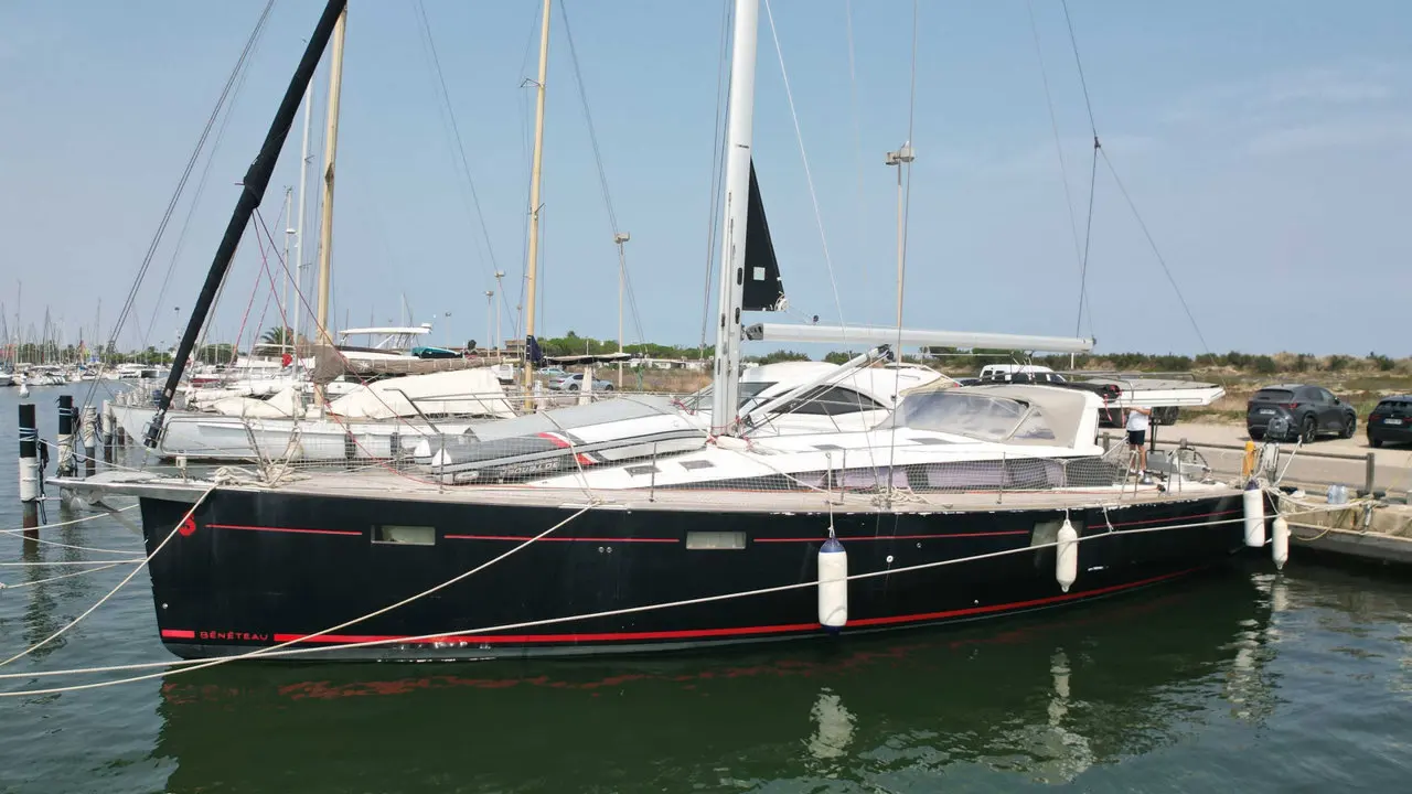 Beneteau Sense 51 — Voilier noir et rouge amarré dans un port de plaisance.