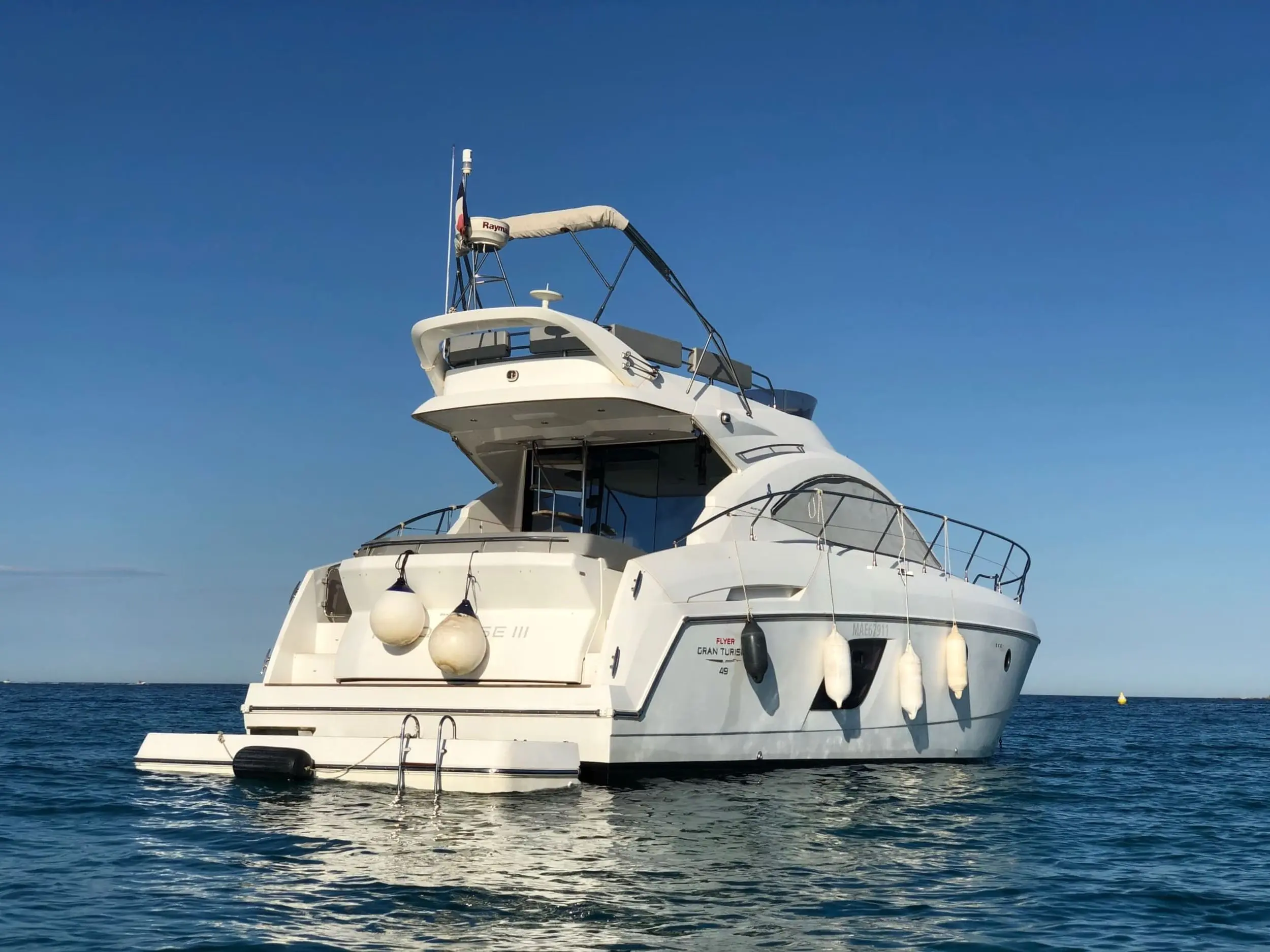 Beneteau Gran Turismo 49 — Bateau à moteur blanc vu de trois quarts arrière, amarré sur une mer calme.