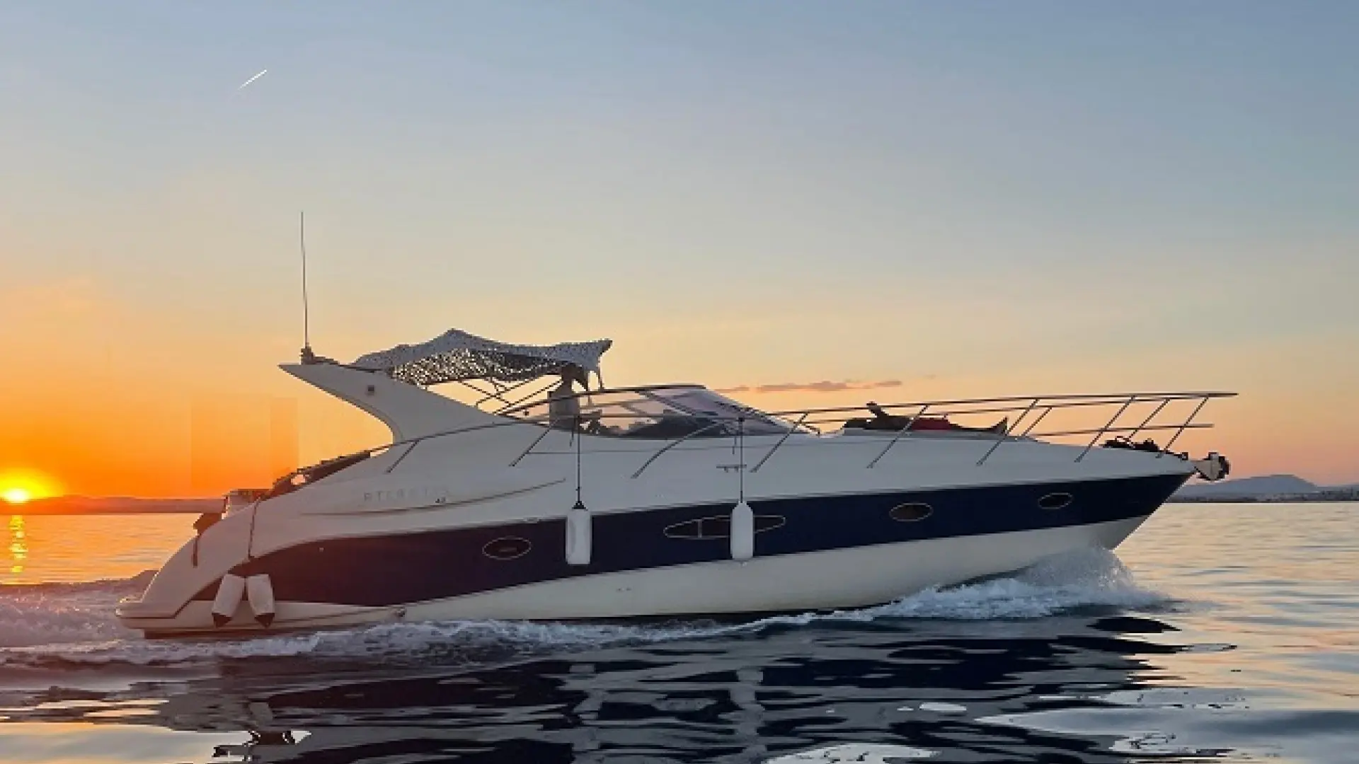 Atlantis 42 — Bateau à moteur naviguant de profil au coucher du soleil.