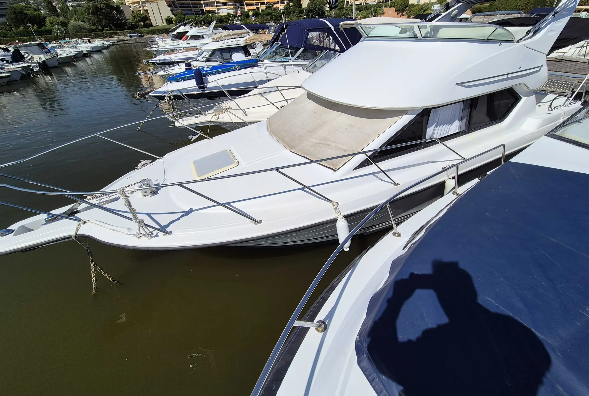 Bayliner 2858 Fly — Bateau à moteur blanc amarré dans une marina, vu de trois quarts avant.