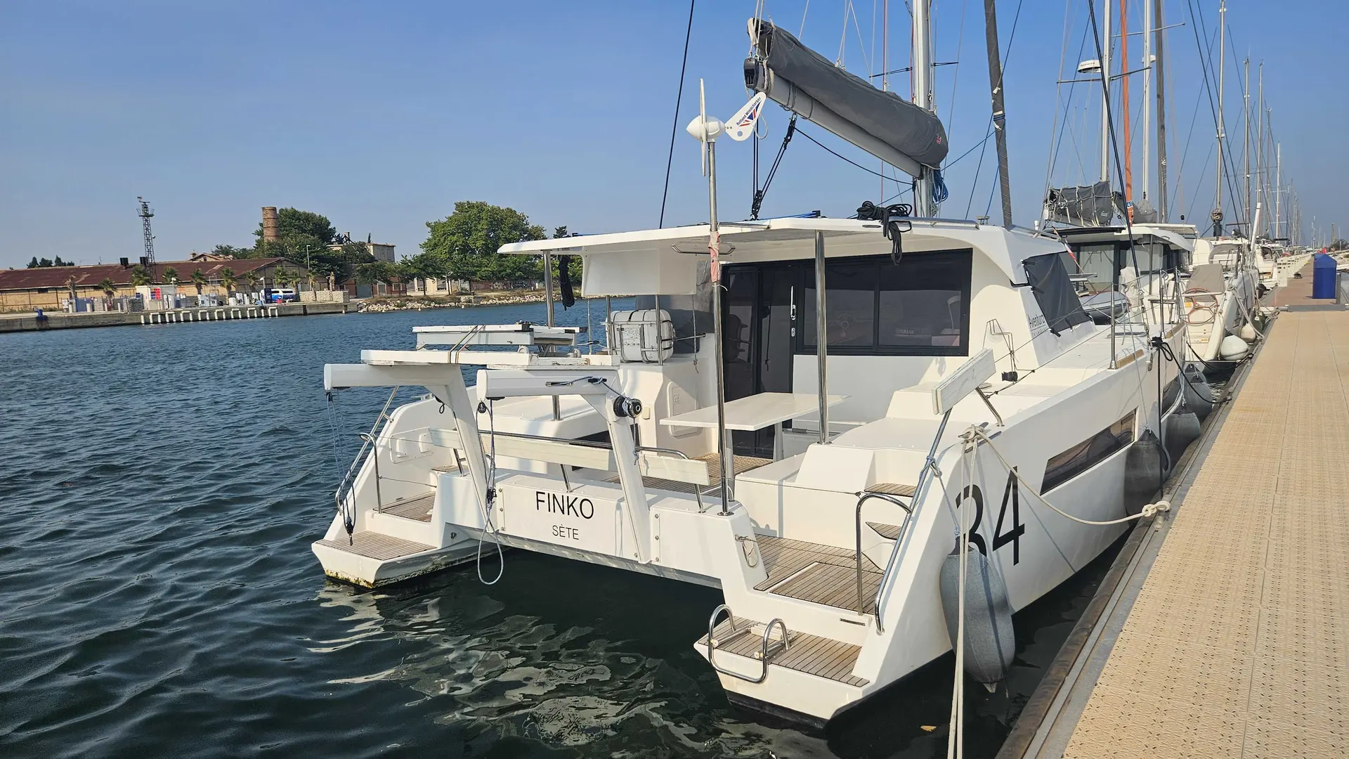Aventura Yacht 34 — Catamaran blanc amarré dans un port, vu de trois quarts arrière.
