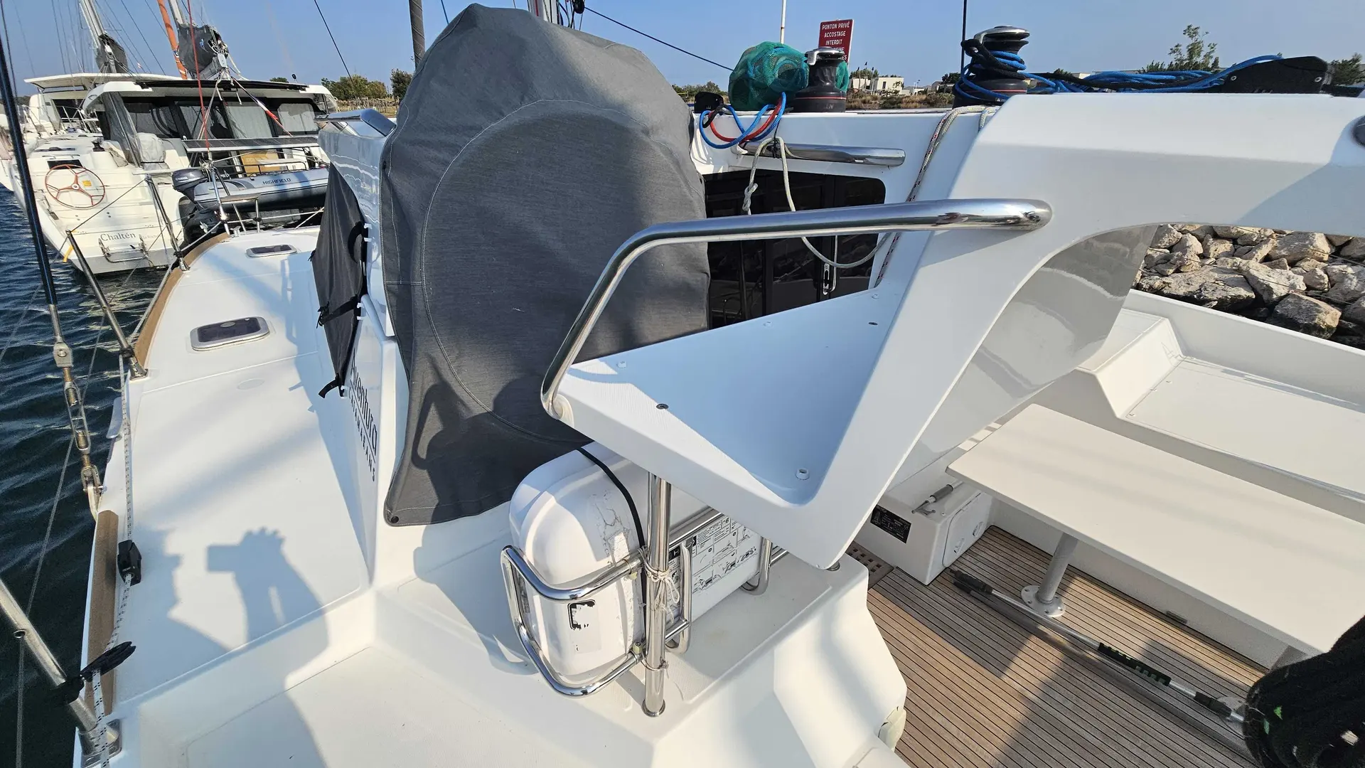 Aventura Yacht 34 — Vue partielle du cockpit arrière d’un catamaran amarré, avec sa barre et son annexe.